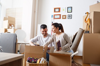Young couple packing cardboard boxes at new home.Moving house. Moving on a budget